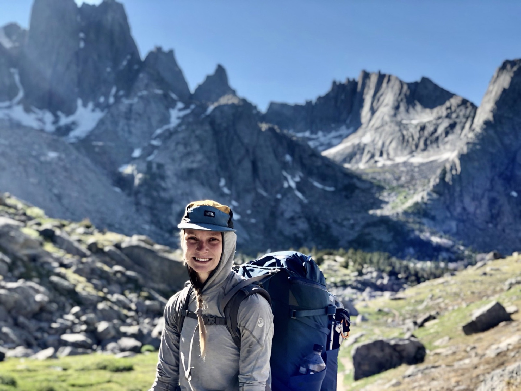 Shea McCrary with a backpack below granite peaks