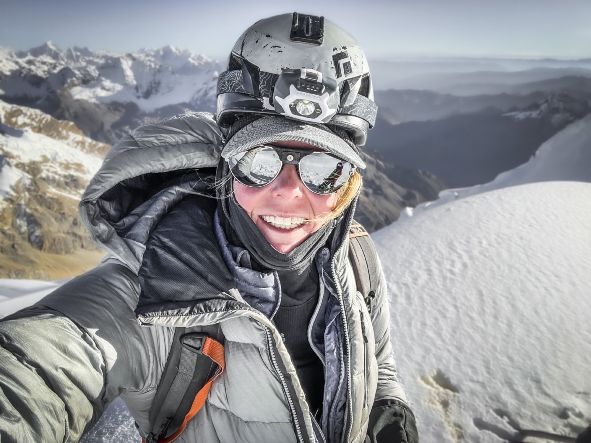 Sunny Stroeer smiling in a helmet and goggles on a snowy summit